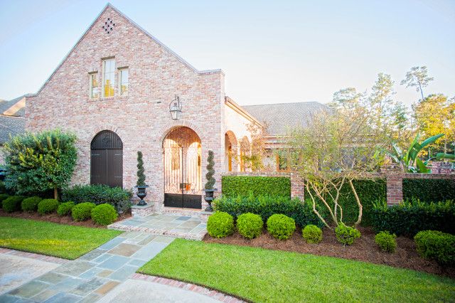 Brick home with manicured boxwood hedges and a landscaped front yard in St. Tammany Parish